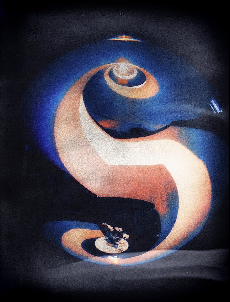 A vertical infrared and fisheye photograph of a spiral staircase, false-coloured deep blue and cream, coiling into a bright core at the top. The whole form reads as the letter S before it reads as a staircase.