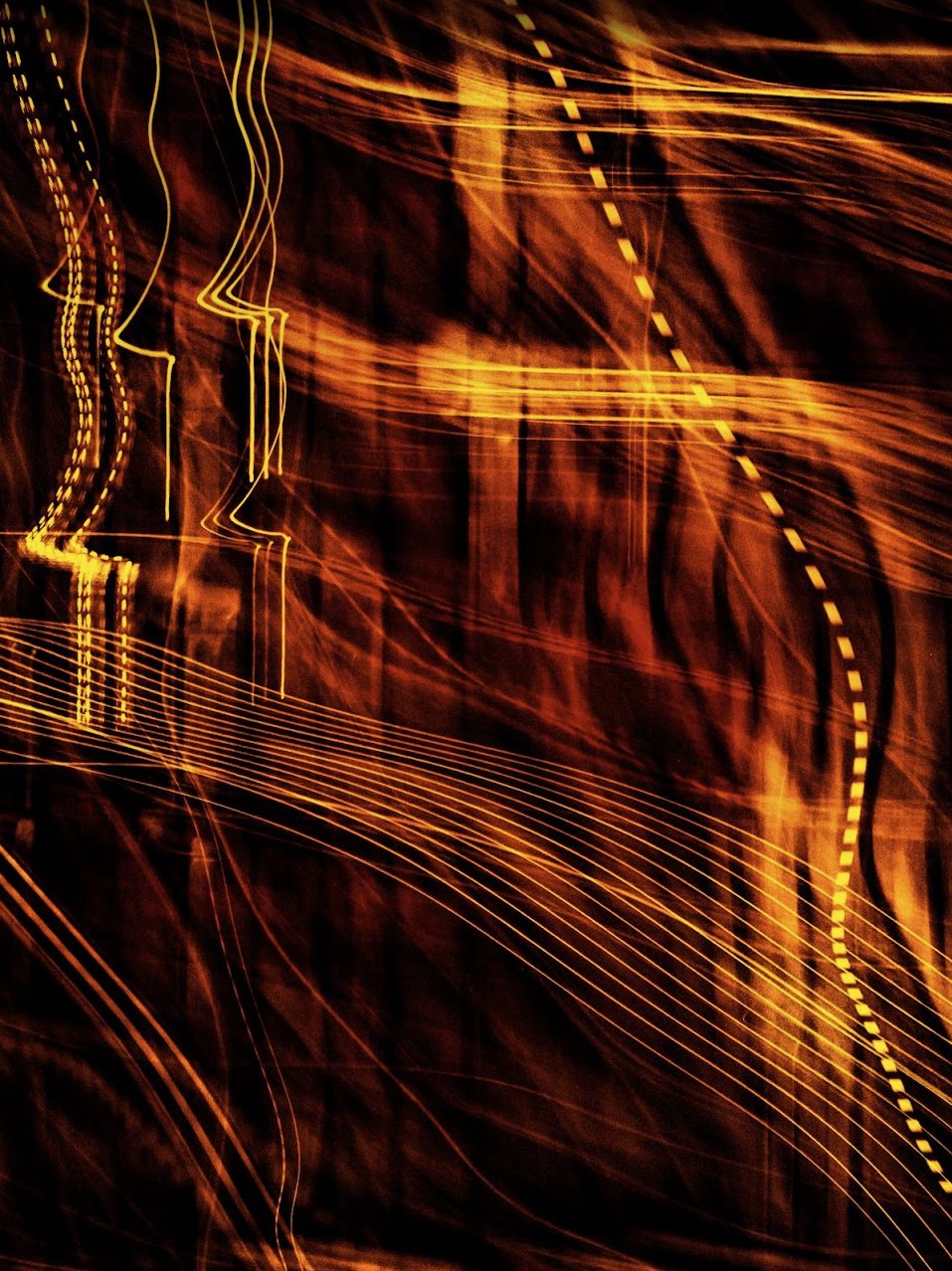 A vertical abstract of amber and gold light trails on near-black, made by moving the camera during a long night exposure. Lines loop, double back and fan out across the frame; one dashed line curves down the right-hand side like a stitched seam.